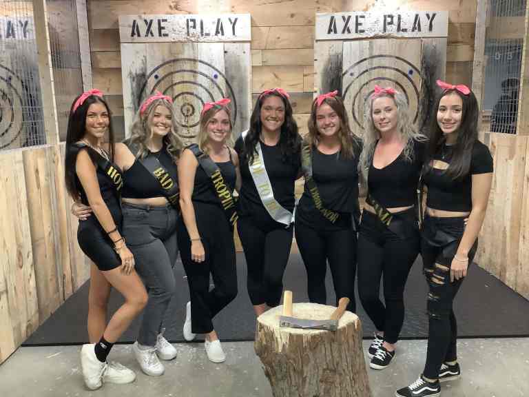 Bachelorette party group posing around stump Axe Play Hudson NH