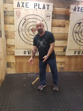 Matt K, co-owner of Axe Play in Hudson NH, standing by an axe target with a smile