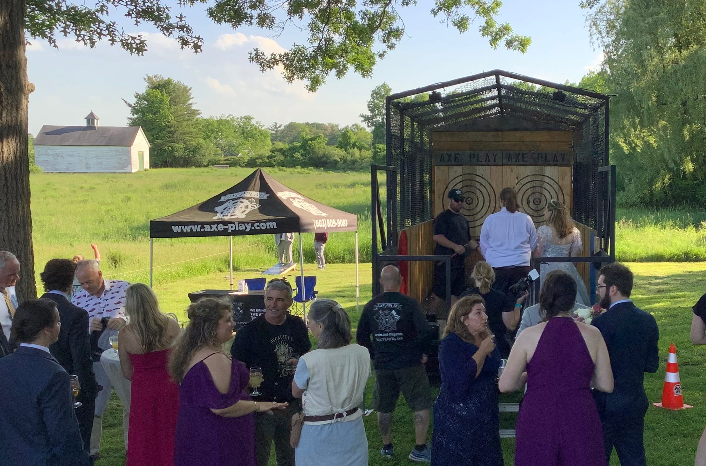 Large group of wedding guests watching the couple enjoy a mobile axe throwing wedding experience