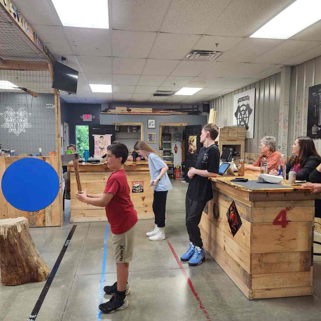 Young thrower learning axe throwing under supervision at Axe Play in Hudson NH.