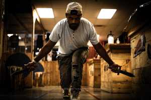 Man crouching with throwing knives at Axe Play bachelor party Hudson NH