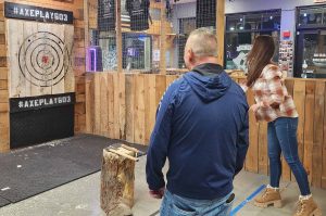 Woman throwing an axe while partner watches