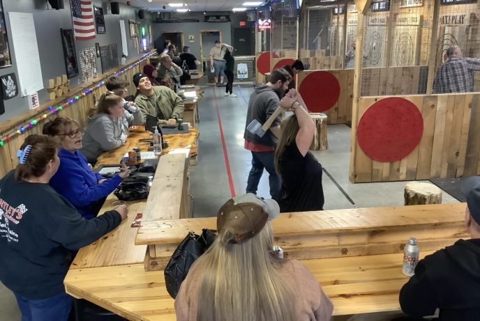 Group of people axe throwing in indoor lanes at Axe Play in Hudson NH with multiple targets and a social atmosphere