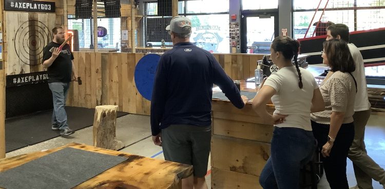 An Axe Play Axepert explains safe axe throwing techniques to first-time guests before they begin throwing in Hudson, New Hampshire.