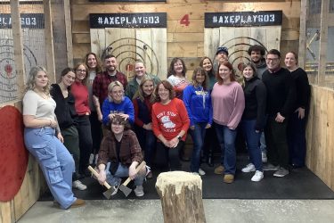 Company employees posing for a group photo after a holiday party at Axe Play axe throwing venue.