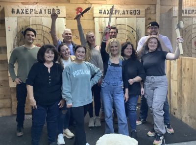 Coworkers celebrating together while holding axes after a successful holiday party.