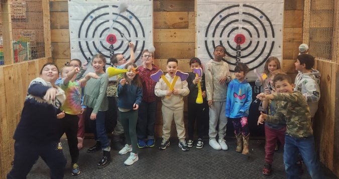 Children posing with Velcro axes in front of the targets during a Little Warriors birthday party at Axe Play.